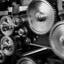 Close-up macro photograph of interlocking metal cogs and gears in a mechanical clockwork mechanism, in black and white
