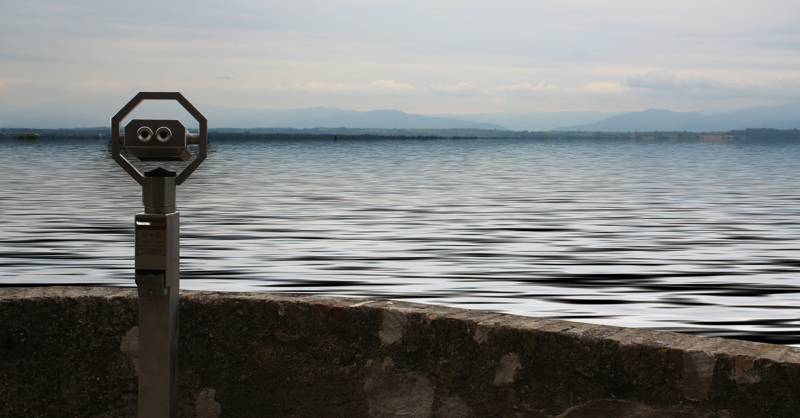 Viewing telescope overlooking a calm lake with distant mountains in the background.