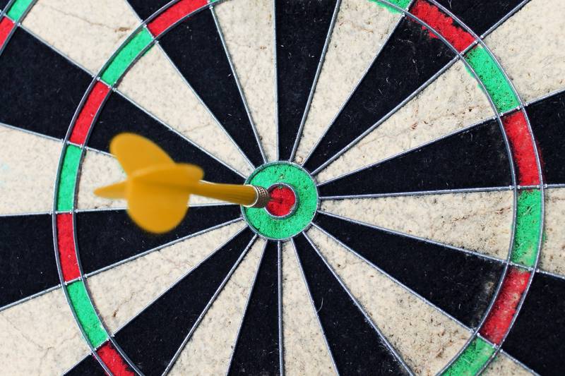 Close-up of a dartboard with a yellow dart in the bullseye.