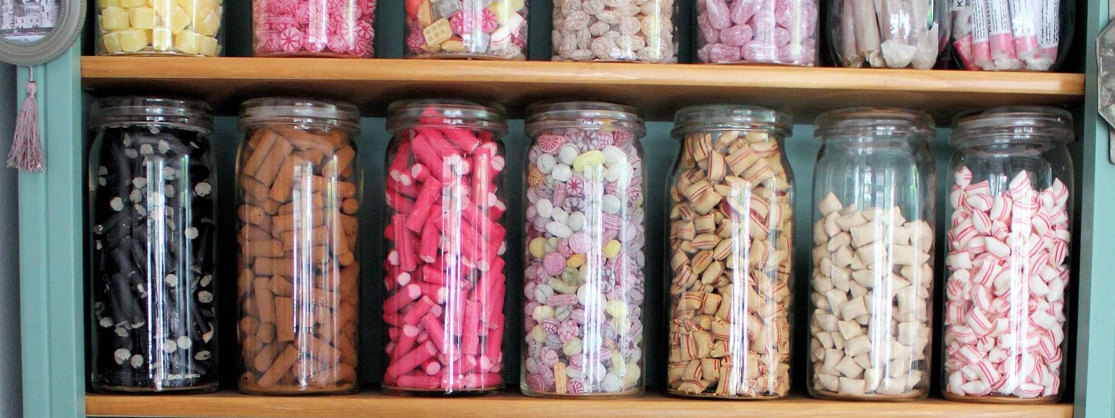A colourful display of jars filled with various sweets on a wooden shelf.