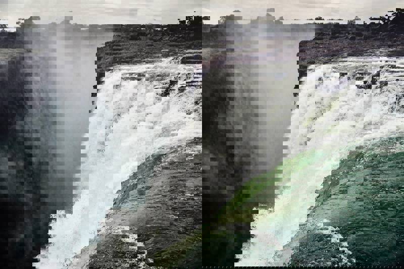 Close-up of a waterfall cascading over a rocky edge into misty surroundings.