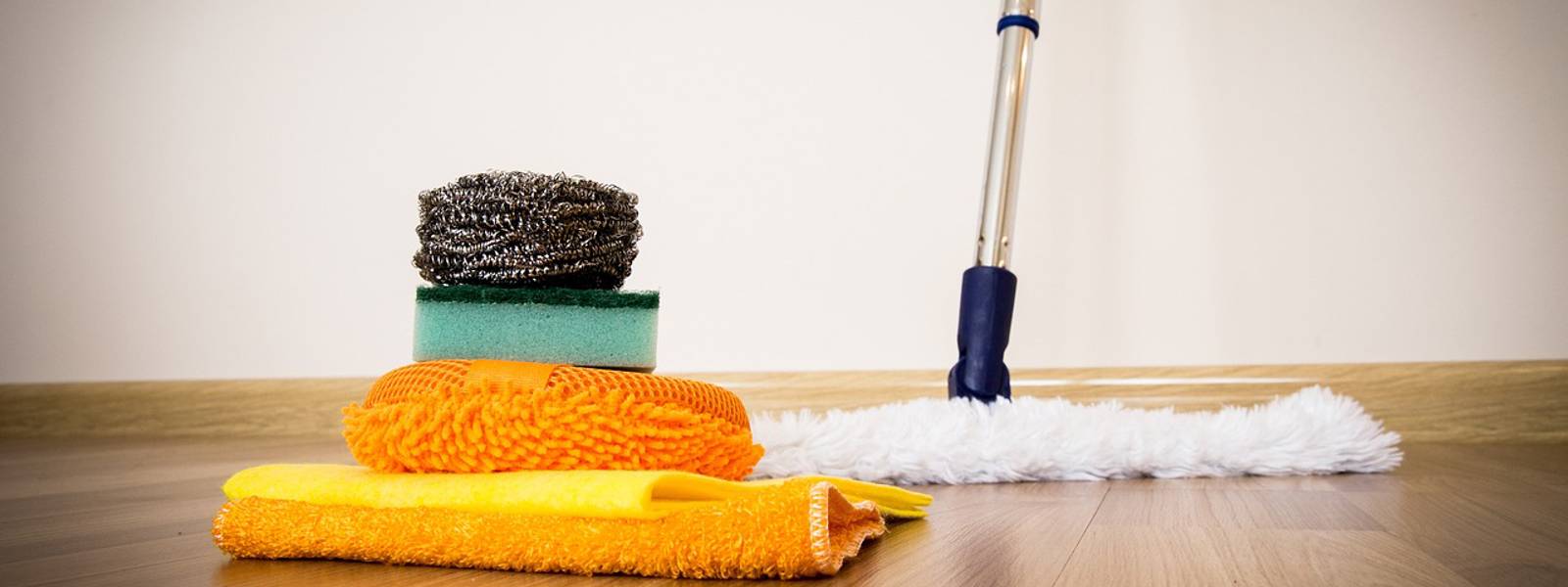 A stack of cleaning cloths and a mop on a wooden floor, ready for cleaning tasks.