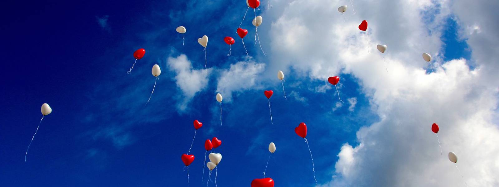 A sky filled with red and white balloons against a blue backdrop.