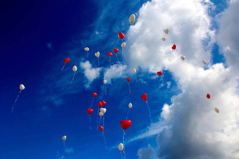 A sky filled with red and white balloons against a blue backdrop.